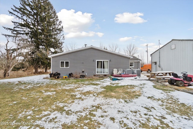 snow covered back of property with a wooden deck