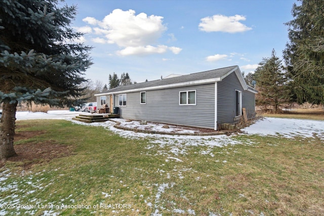 snow covered rear of property with a yard