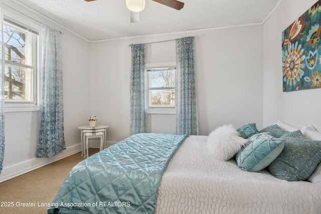 bedroom with ceiling fan, carpet floors, ornamental molding, and a textured ceiling