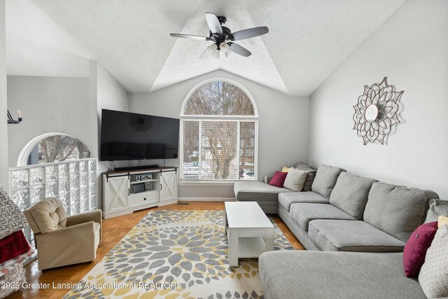 living room featuring ceiling fan, vaulted ceiling, and a textured ceiling