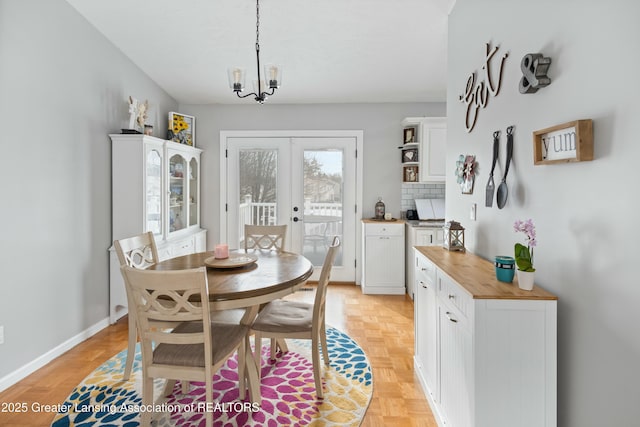 dining area featuring light parquet floors, a notable chandelier, and french doors