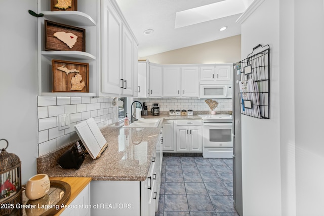 kitchen featuring vaulted ceiling with skylight, sink, white cabinets, decorative backsplash, and white appliances