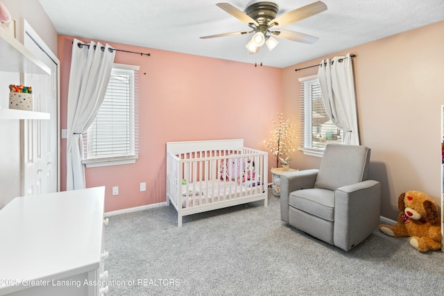 bedroom featuring a crib, light colored carpet, and ceiling fan