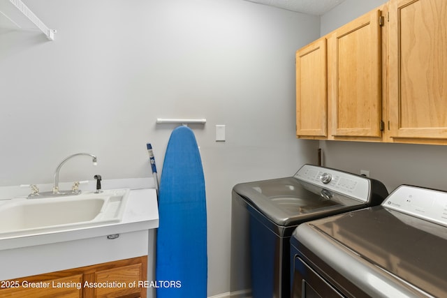 washroom featuring washer and dryer, sink, and cabinets