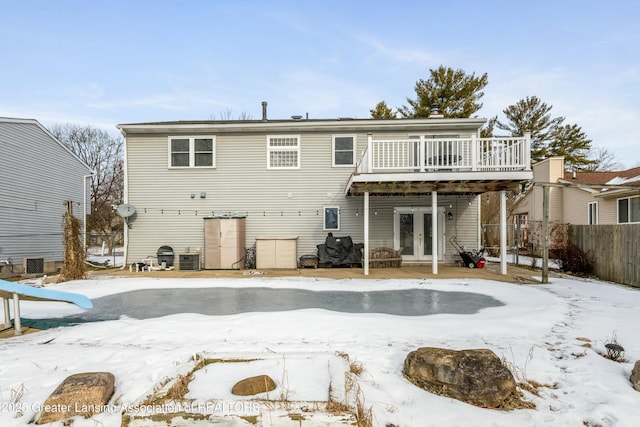 snow covered back of property featuring a deck and central air condition unit