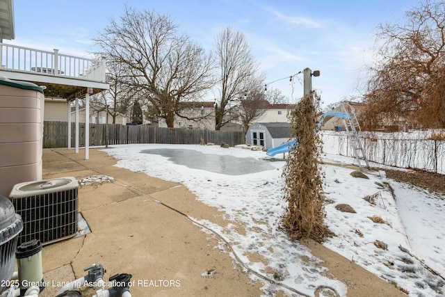 yard layered in snow with cooling unit and a storage unit