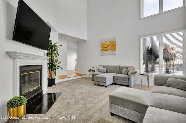 living room featuring a towering ceiling, carpet floors, and a healthy amount of sunlight