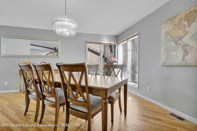 dining space featuring an inviting chandelier and light hardwood / wood-style flooring