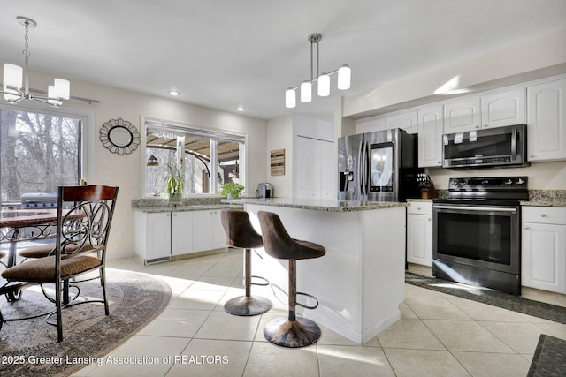 kitchen featuring decorative light fixtures, light tile patterned flooring, white cabinets, and appliances with stainless steel finishes