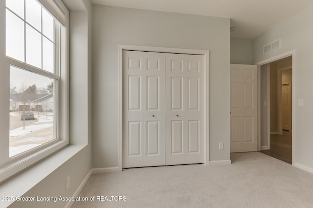 unfurnished bedroom featuring light carpet and a closet