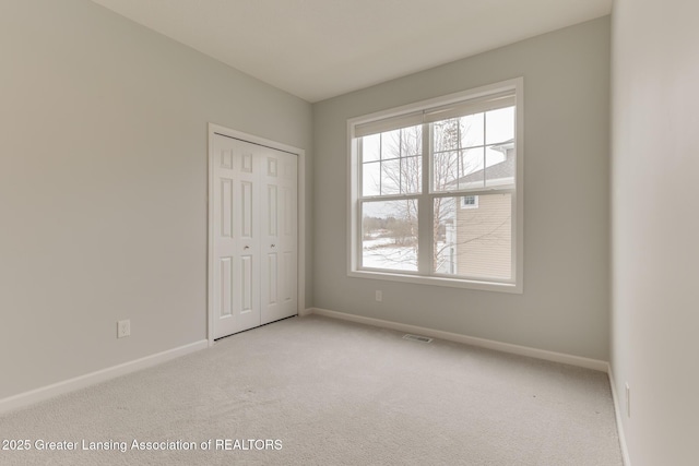 unfurnished bedroom with light colored carpet and a closet