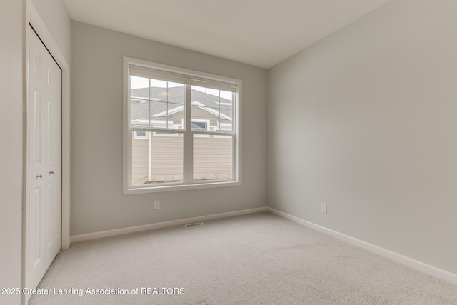 unfurnished bedroom with light colored carpet and a closet