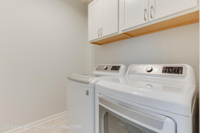 laundry room featuring cabinets, light tile patterned floors, and washer and clothes dryer