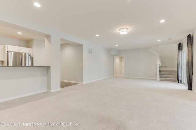 basement featuring light carpet and stainless steel refrigerator