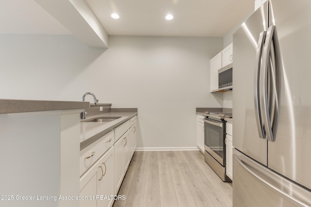 kitchen with white cabinetry, sink, stainless steel appliances, and light hardwood / wood-style floors