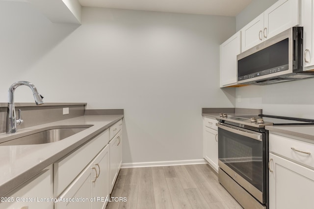 kitchen featuring white cabinetry, appliances with stainless steel finishes, sink, and light hardwood / wood-style floors