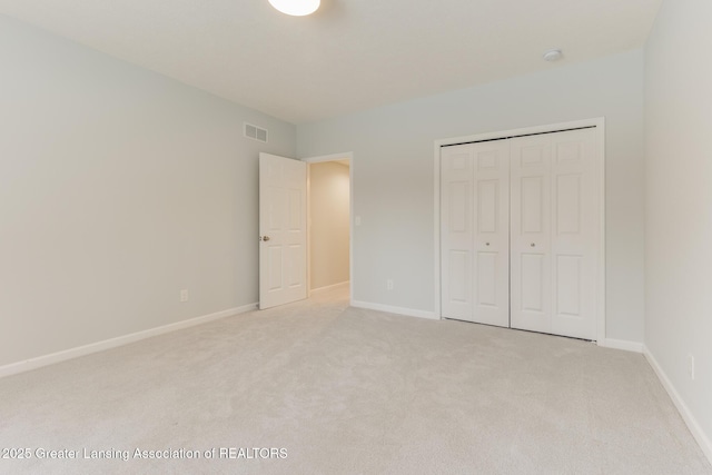 unfurnished bedroom with light carpet and a closet