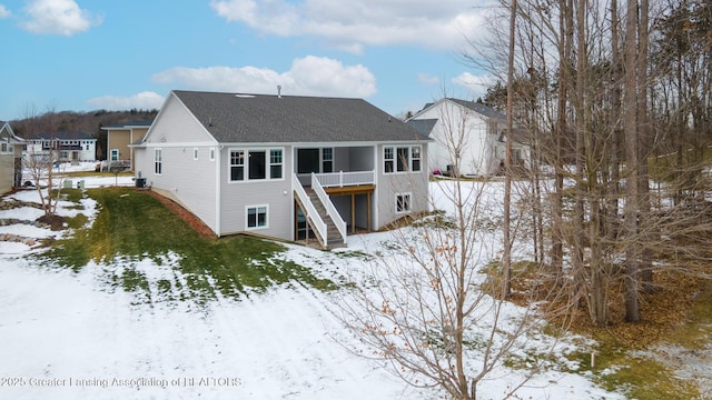 snow covered back of property with a deck