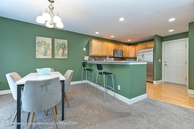 kitchen with pendant lighting, a breakfast bar area, stainless steel appliances, tasteful backsplash, and kitchen peninsula