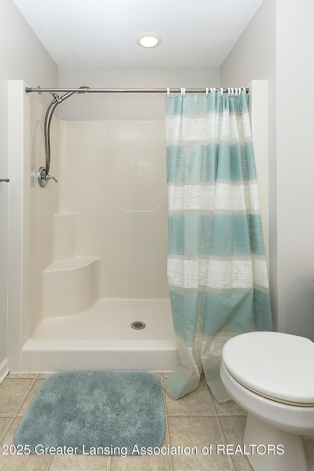 bathroom with tile patterned floors, toilet, and a shower with shower curtain