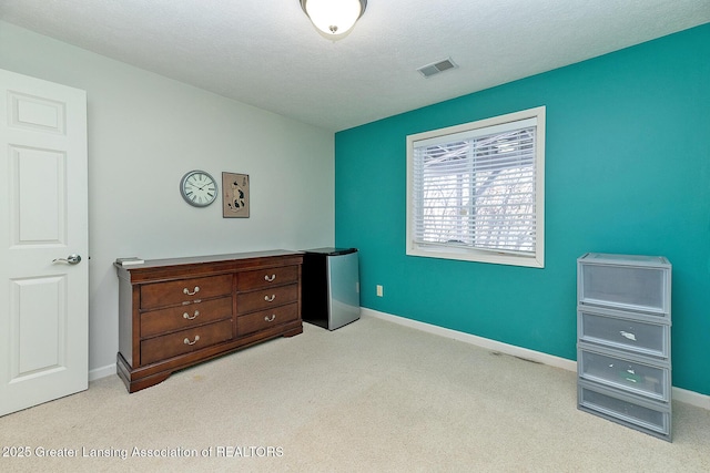 carpeted bedroom featuring stainless steel refrigerator and a textured ceiling