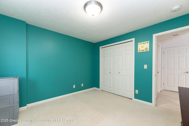 unfurnished bedroom with light carpet, a closet, and a textured ceiling