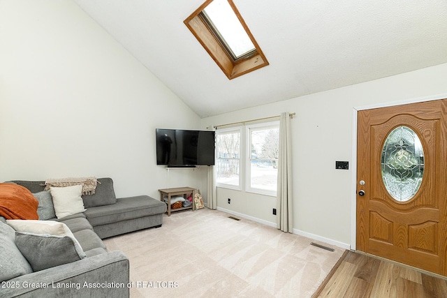 living room with a skylight, high vaulted ceiling, and light hardwood / wood-style floors