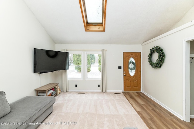 foyer featuring lofted ceiling with skylight and light hardwood / wood-style flooring