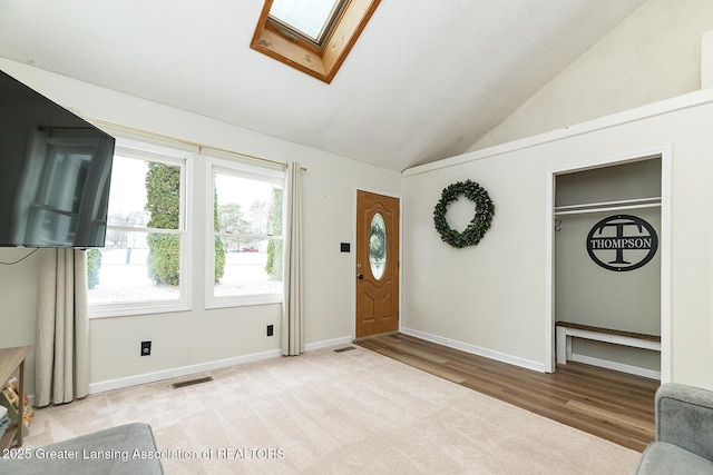 foyer entrance featuring lofted ceiling with skylight and light wood-type flooring