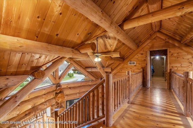 hall with wood ceiling, lofted ceiling with beams, light hardwood / wood-style floors, and log walls