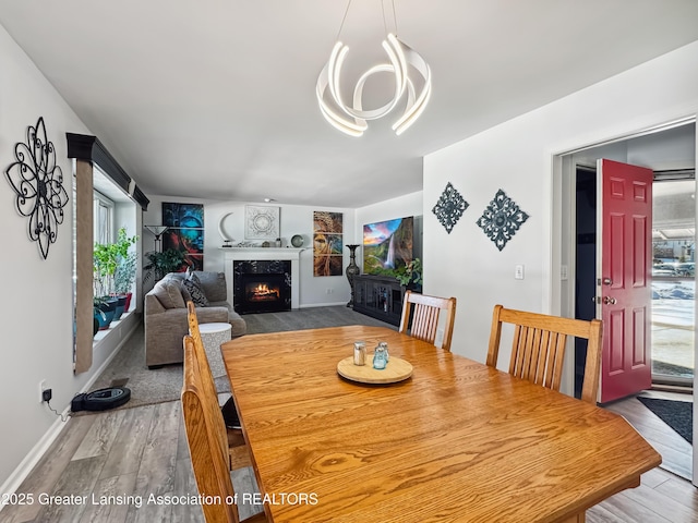 dining area featuring a high end fireplace, wood-type flooring, and a chandelier