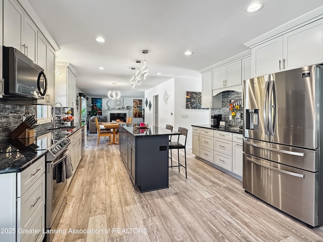 kitchen with stainless steel appliances, decorative light fixtures, a center island, and white cabinets