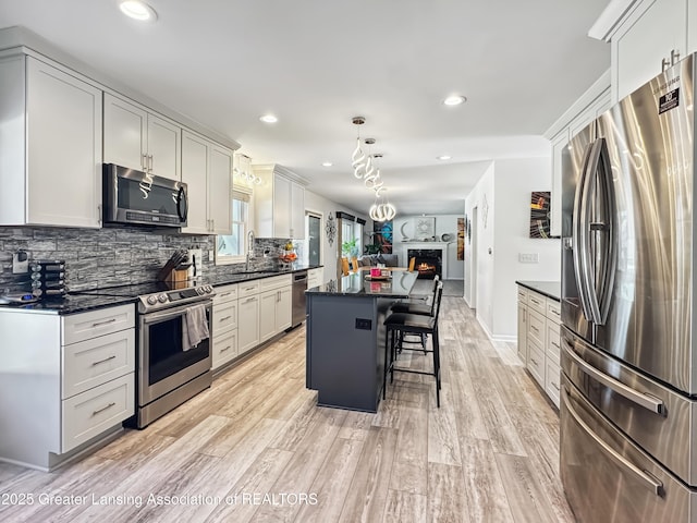 kitchen with a kitchen bar, decorative backsplash, hanging light fixtures, a center island, and stainless steel appliances