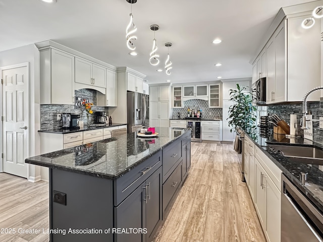 kitchen featuring appliances with stainless steel finishes, decorative light fixtures, sink, wine cooler, and a center island