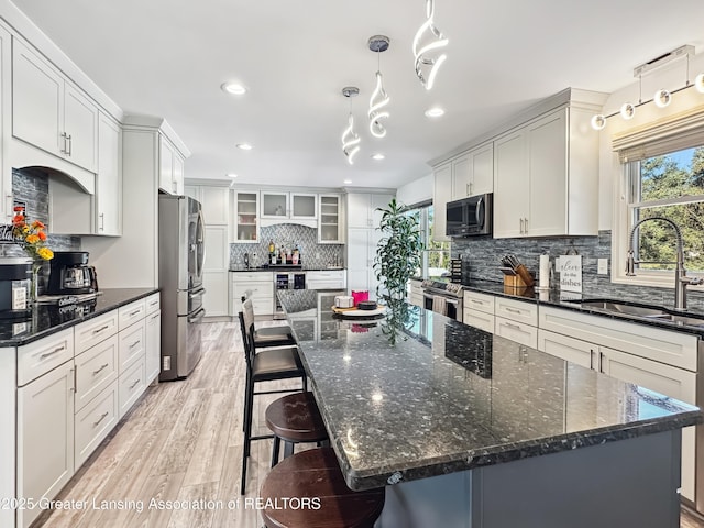 kitchen with white cabinetry, appliances with stainless steel finishes, decorative light fixtures, and sink