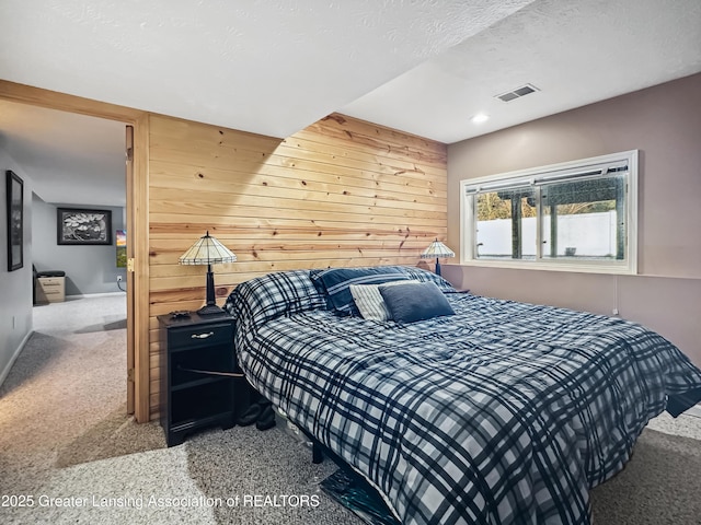 carpeted bedroom featuring a textured ceiling and wood walls