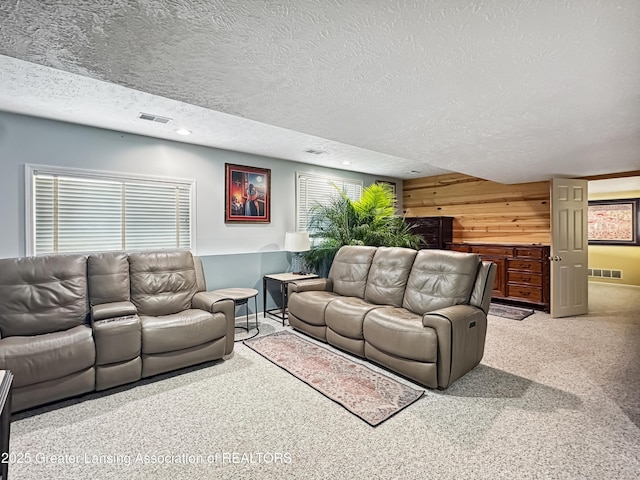 carpeted living room featuring wooden walls and a textured ceiling