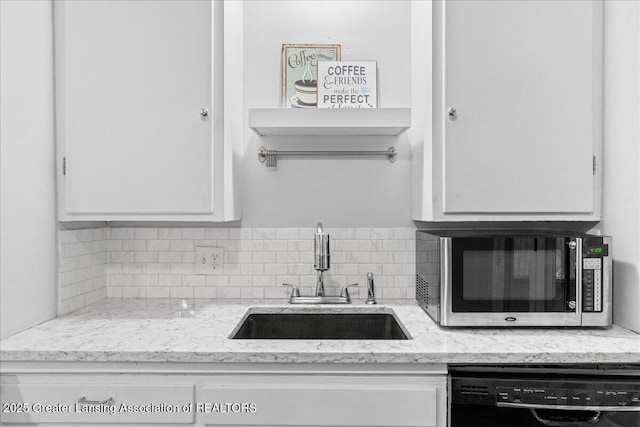 kitchen with light stone counters, dishwasher, sink, and white cabinets