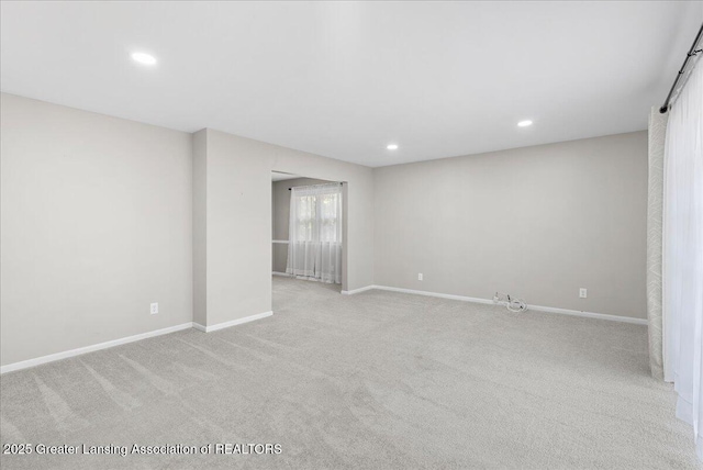 spare room featuring recessed lighting, light colored carpet, and baseboards