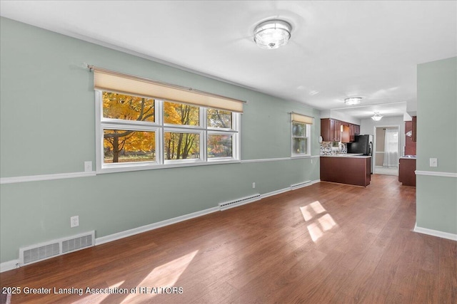 unfurnished living room featuring dark wood finished floors, baseboards, and visible vents