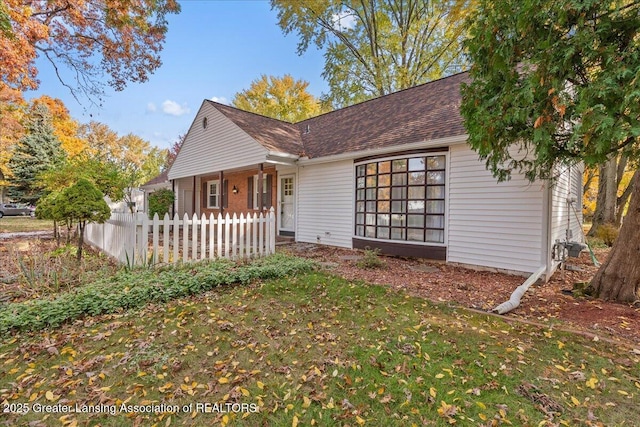 view of front of property with a front yard, fence, and roof with shingles