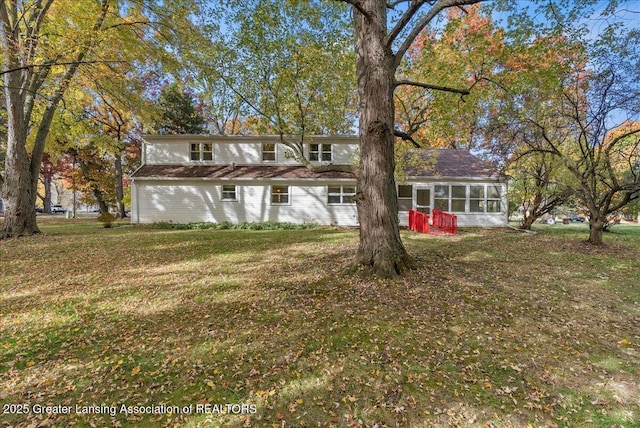 rear view of property with a lawn and a sunroom