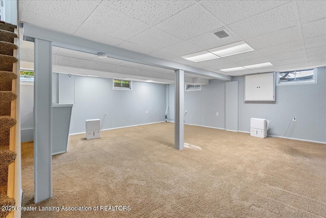 basement featuring stairway, carpet flooring, plenty of natural light, and a drop ceiling