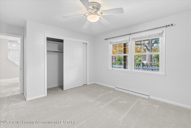 unfurnished bedroom featuring baseboards, a closet, baseboard heating, and carpet floors