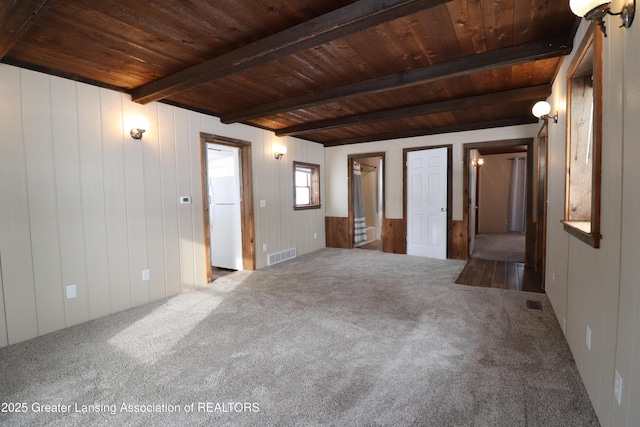 carpeted empty room featuring beamed ceiling and wooden ceiling