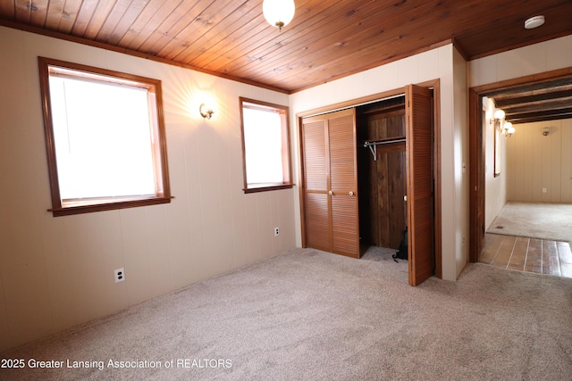 unfurnished bedroom featuring carpet floors, wooden ceiling, and a closet