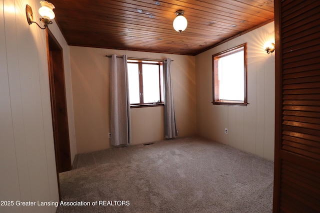 carpeted spare room featuring wooden ceiling