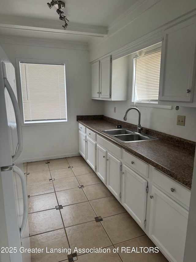 kitchen featuring white refrigerator, light tile patterned floors, sink, and white cabinets