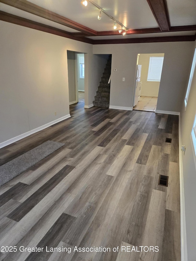 unfurnished living room with beam ceiling, hardwood / wood-style flooring, and a wealth of natural light