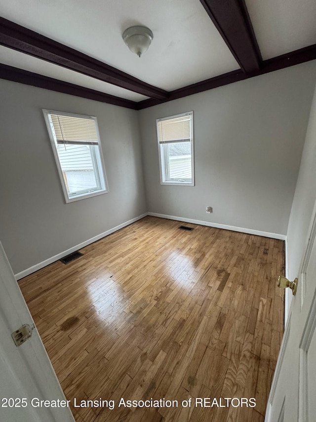 unfurnished room with wood-type flooring and beamed ceiling